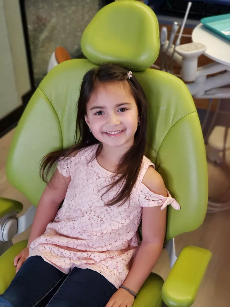 Small child sits in a children's chair especially made for smaller frames for dentistry for children services at ABC Dentistry in Schaumburg IL.