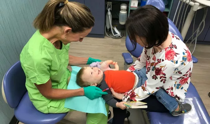 dentist from ABC Dentistry checking on a young patient's teeth