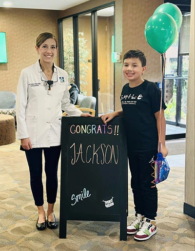 pediatric patient posing with dentist after post-orthodontic treatment